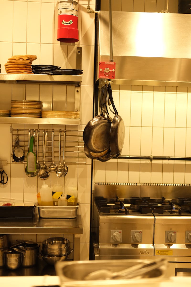 A well-equipped industrial kitchen with hanging pans and cooking utensils.